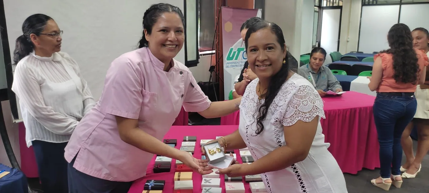 Dos trabajadoras posan con un obsequio durante la actividad del Día de las Madres