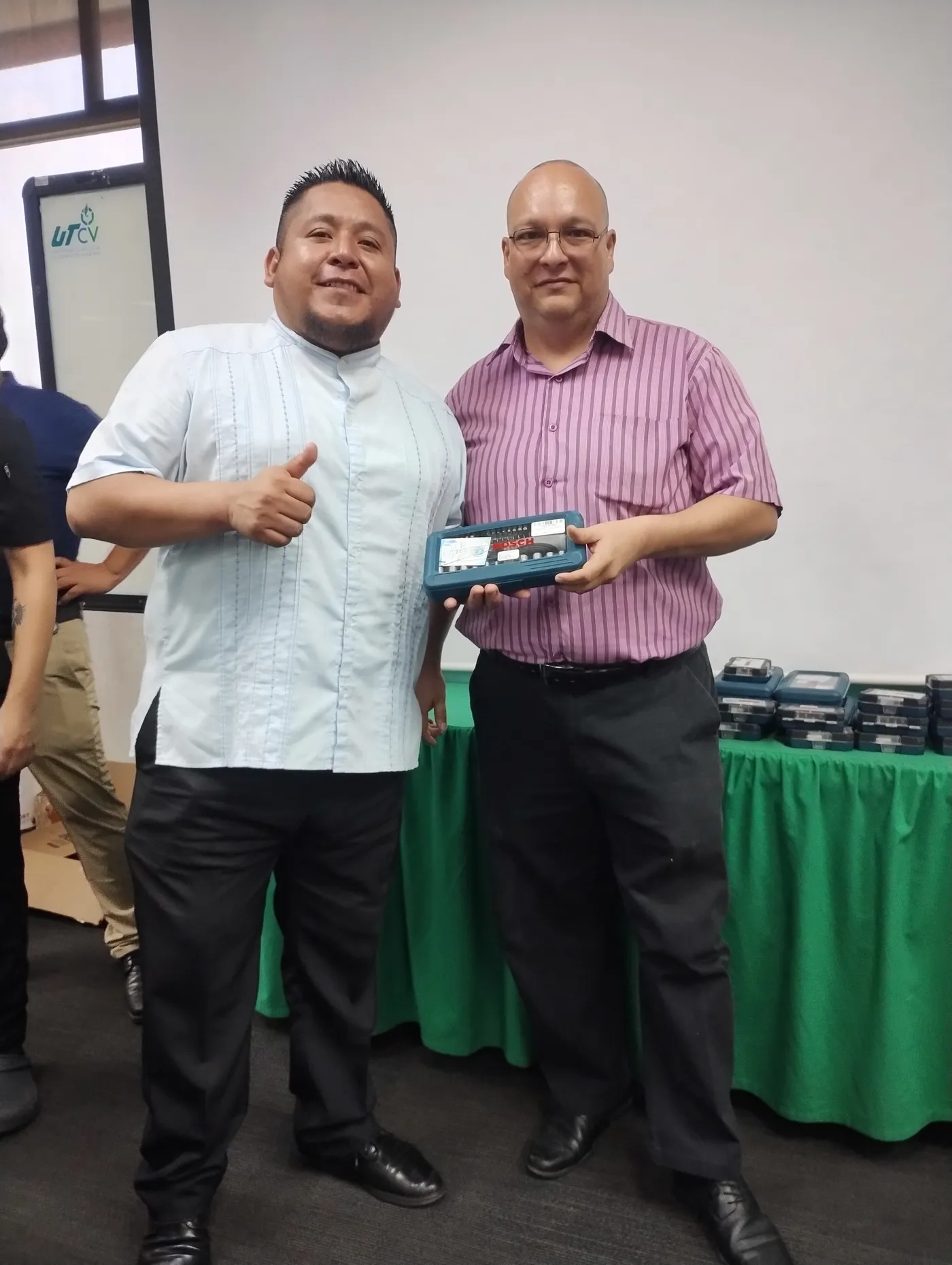 Dos trabajadores posan con un juego de herramientas recibido como obsequio