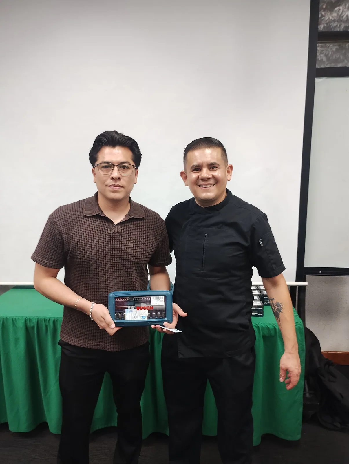 Dos integrantes de la comunidad universitaria sostienen un juego de herramientas